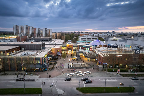 Ansicht auf ein Shopping-Center-Gelände von außen und befahrener Straße.