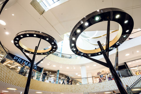 Blick auf zwei modern gestaltete Lampeninstallationen im Inneren eines Shopping-Centers.
