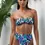 Thumbnail: Model wearing a tropical leaf print bandeau bikini top in teal, plum, and white - Botanical print