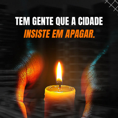 mãos ao redor de uma vela acesa, fundo escuro e frase "Tem gente que a cidade insiste em apagar"
