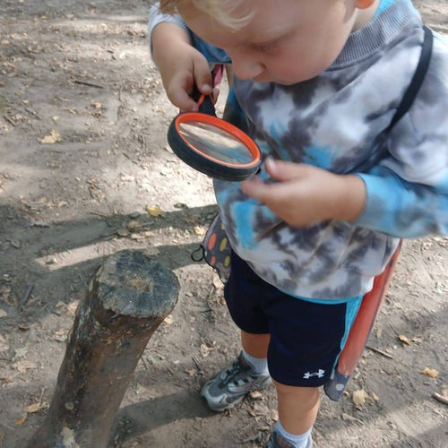 A child studying something closely with a magnifying glass