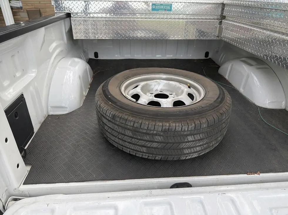 Spare tire and toolbox in the bed of a white pickup truck