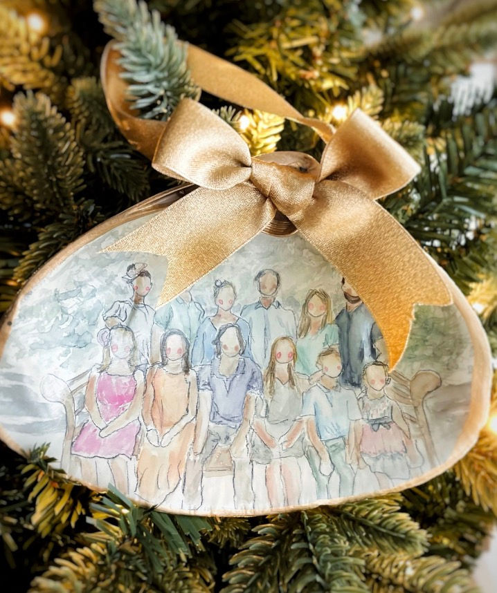 Thumbnail: A large family painted on the inside of a clam shell and finished with gold ribbon hanging on a Christmas tree.