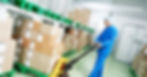 A medical warehouse worker using a manual lift loader to transport packed medical equipment to ensure safe moving.