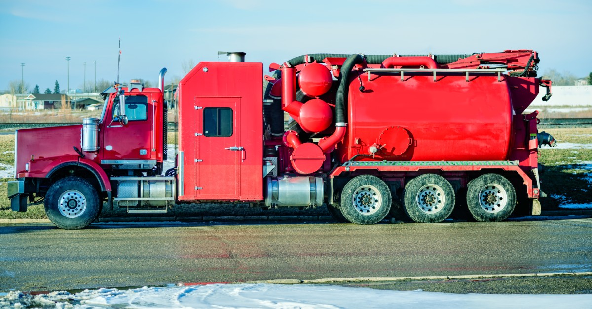 A red truck with hoses running along its side. It’s parked on a road and there’s snow in the foreground.