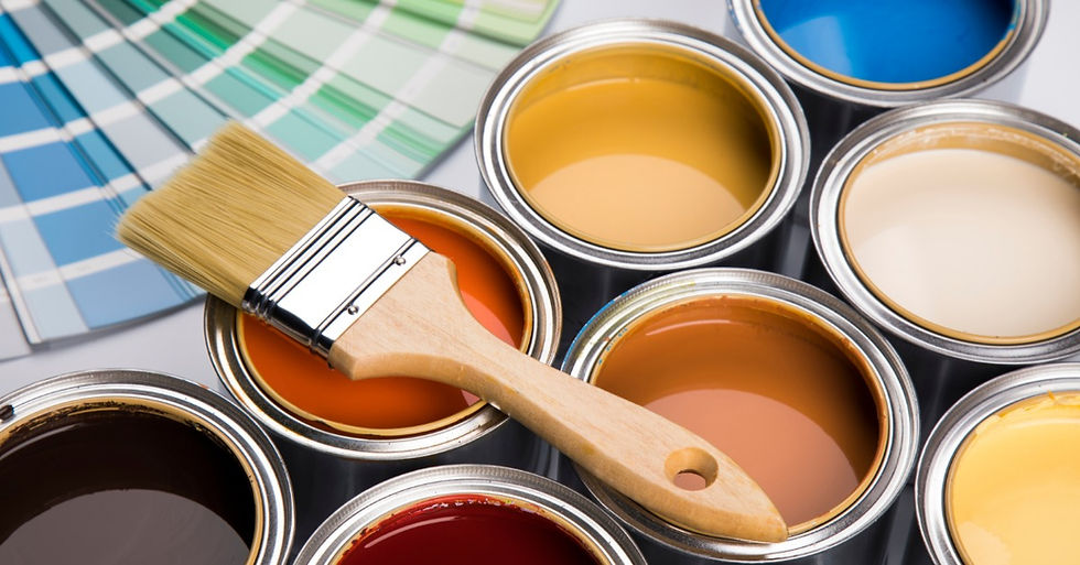 Open paint cans in varied colors sit on a work surface, with a paintbrush across one can and color swatches nearby.