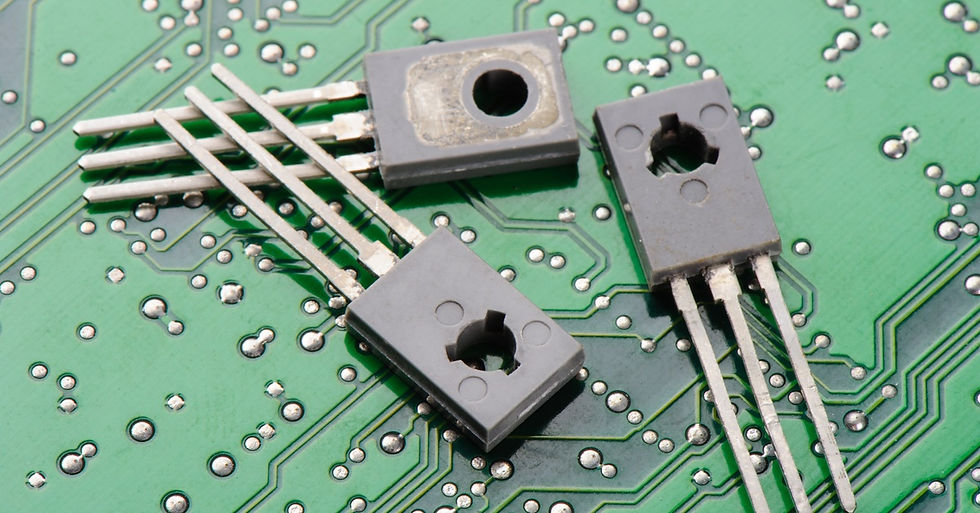 Three tiny transistors used in modern electronics sit on top of a green and silver hard-drive panel.