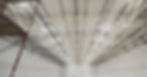 A group of construction workers are installing white flooring and ceiling insulation in a large warehouse.