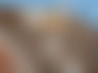 Several people are on a roof of a house. They are all wearing protective gear as they tear the roof apart.