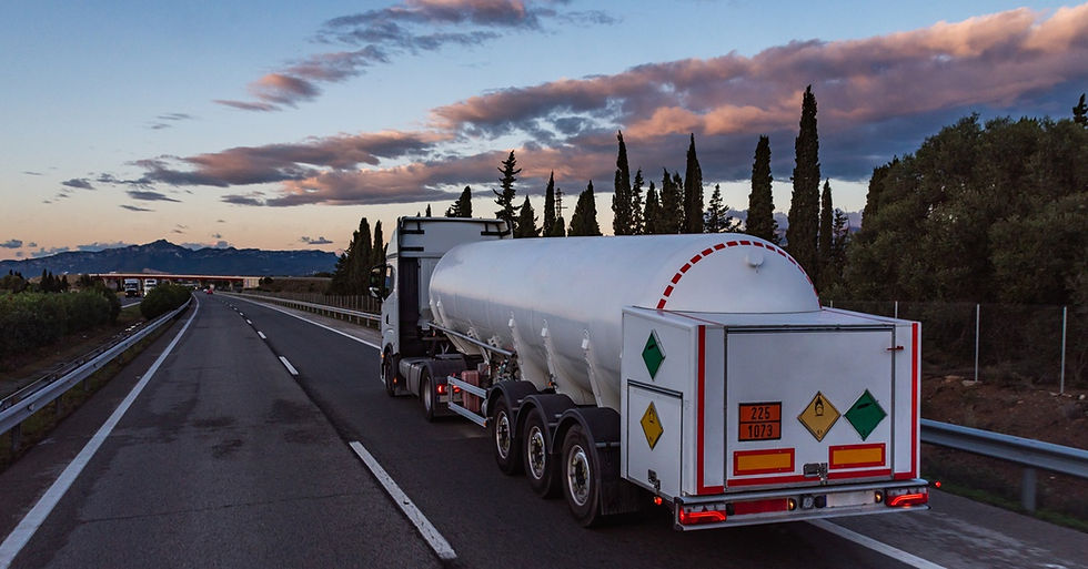  A semi-truck with a white trailer is driving down a road. It is the only vehicle on that road.