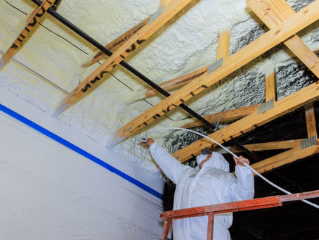 A person is standing on a raised platform and is using a machine to install a foam material on the ceiling.