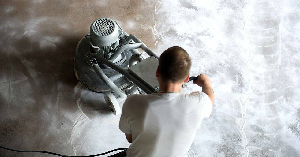 A man uses a concrete grinder to buff the floors, with one half clean and polished while the other is covered in powder.