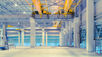 Yellow tracks are the ceiling of a warehouse with a crane hanging below the tracks. The warehouse is empty.