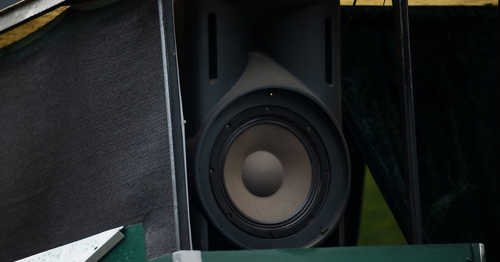 A close-up of a large, black, outdoor speaker set up on a green and gray support with other supports built around it.