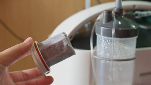 A medical worker checks an oxygen tank in a hospital room, turns the valve knob, and reads the pressure.