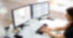 A woman sitting at her desk in front of a computer with payroll software on the screen for better financial management.