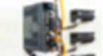 A close-up of a CNC servo controller system mounted to a white wall with three CNC servers in the background.