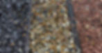 Three different types of rocks in a row, separated by black, wooden boards. The rocks are in different neutral colors.
