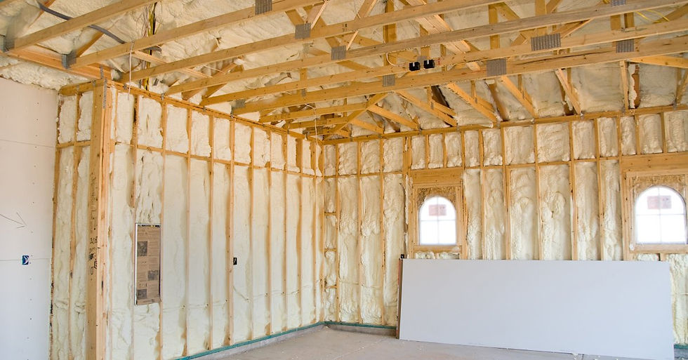 A large room with exposed wooden infrastructure that contains white foam insulation between the beams.