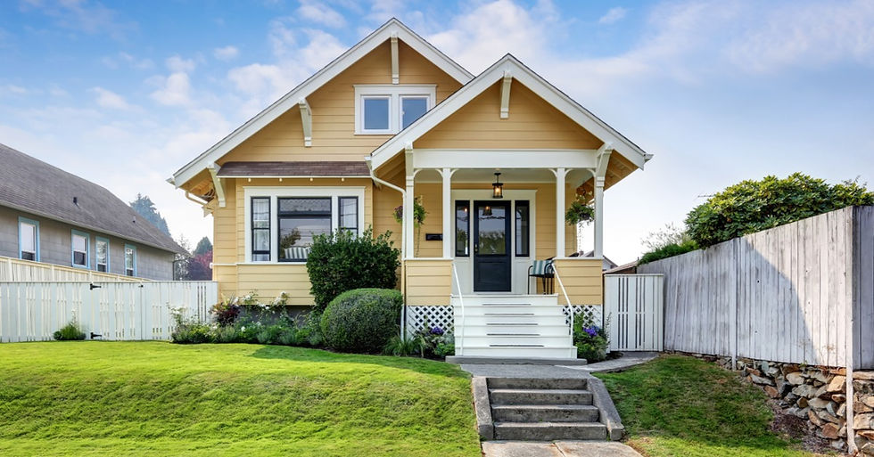 A yellow two-story house with white trim, front steps, and fences. The front lawn and bushes are well-kept.