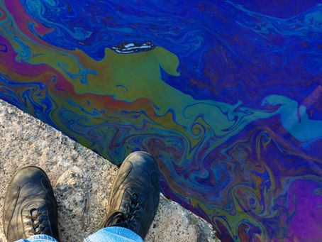 A person in blue jeans and black boot is standing on a ledge. Beyond the ledge is a chemical substance.