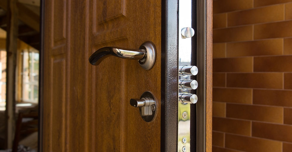 The open front door of a house with multiple deadbolt locks on it. The door is wooden with metal hardware.