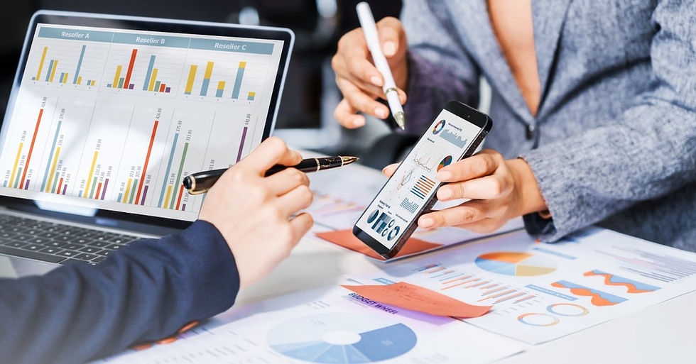 Two business professionals review charts and graphs on a tablet. One person shows more data on their smartphone.