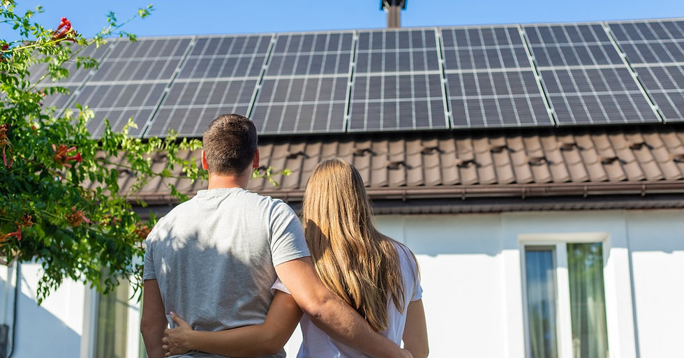 A young couple holding each other while looking at the roof of their home. They have solar panels attached to the roof.