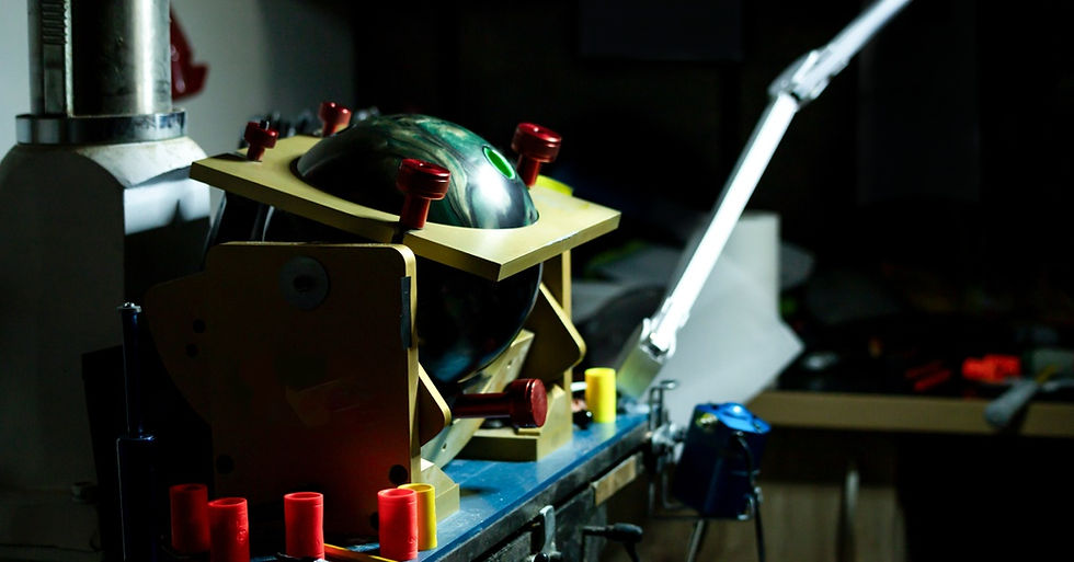 A dark room filled with equipment for drilling bowling balls, with a ball secured in a wooden holder, ready to be drilled.