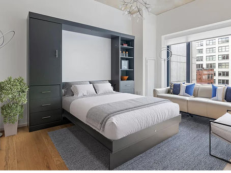A Murphy bed pulled out for someone to use. The bed is in a small room and has cabinets on each side of it.
