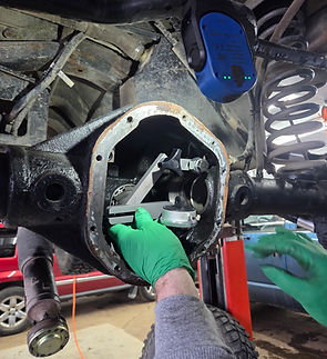 A mechanic measuring and installing new gears into a rear axel.