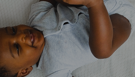 Black baby in grey onesie laying down