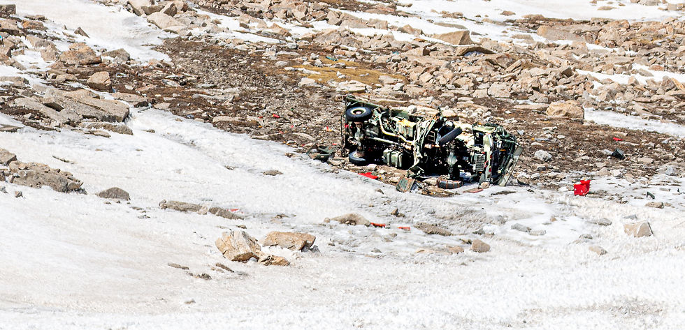 Overturned vehicle on rocky, snowy terrain. Debris scattered around, creating a dramatic, chaotic scene.