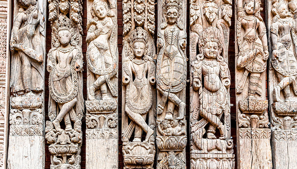 Intricately carved wooden figures on a wall, featuring deities with detailed patterns. The wood's natural tones add a historic feel.