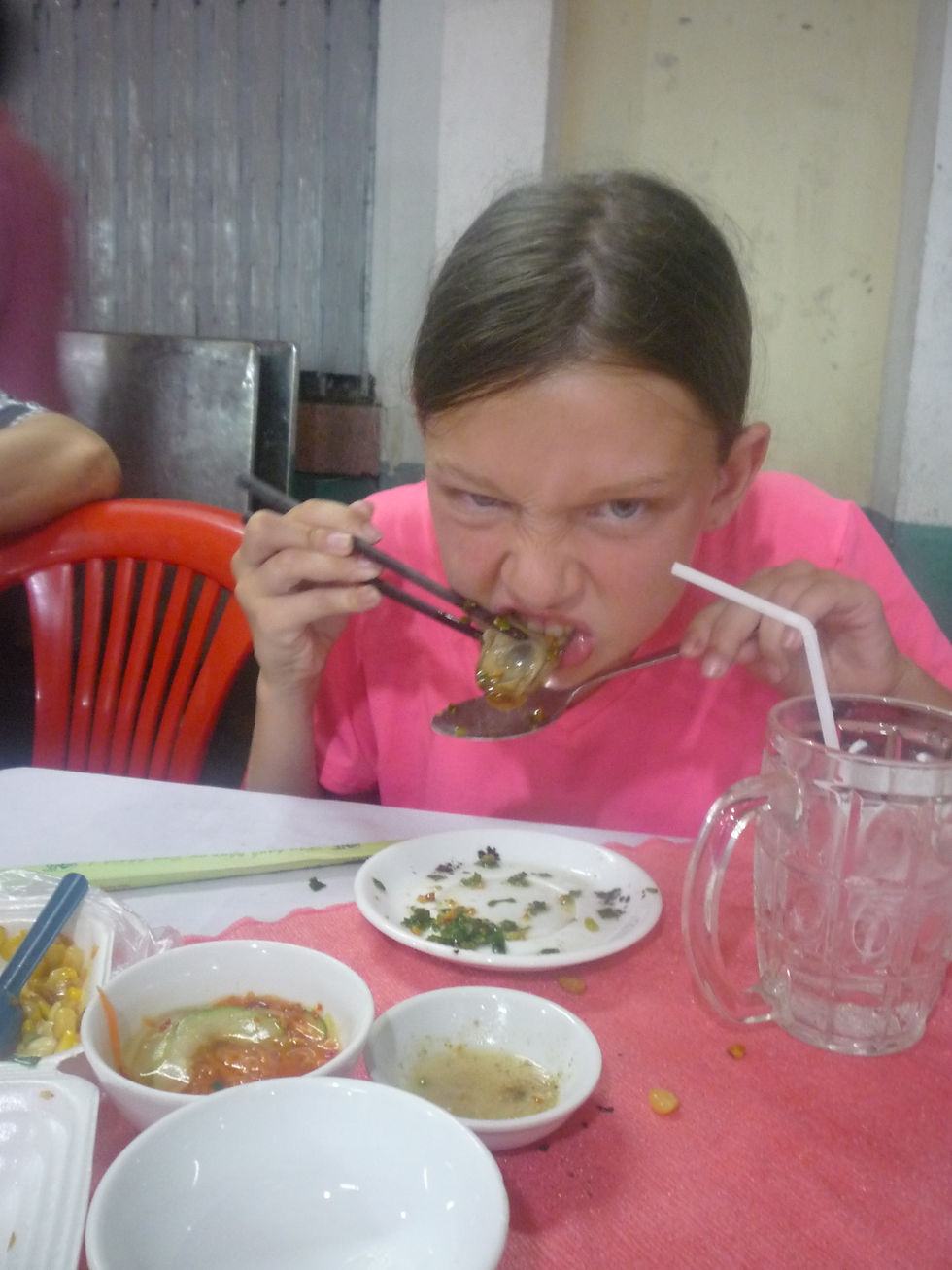 Young girl determinedly eating street food dog with chopsticks at a restaurant in Saigon, Vietnam