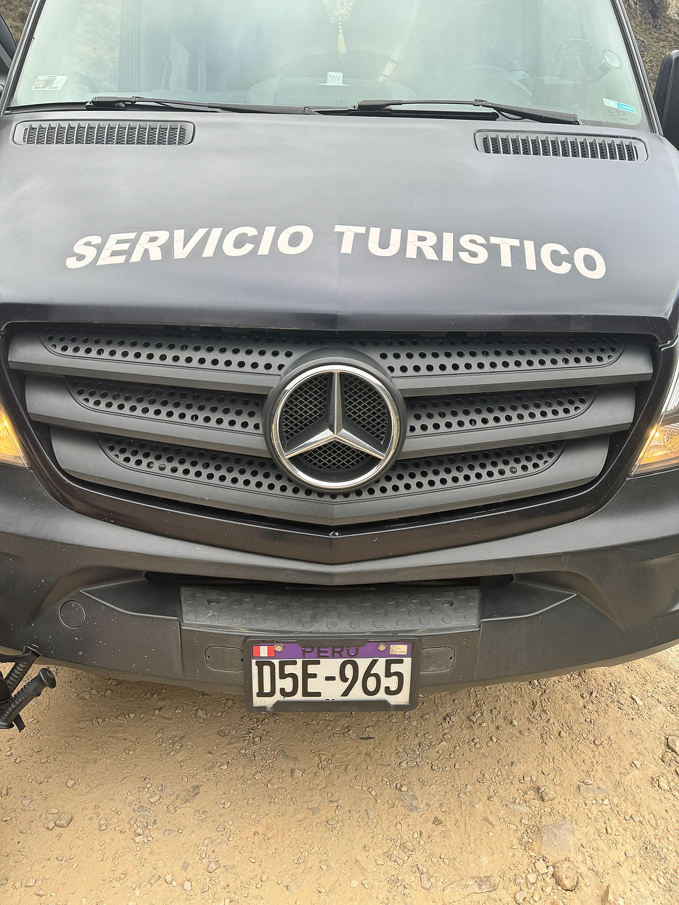 Front of a black tourist service van with "SERVICIO TURISTICO" on the hood. Peruvian license plate D5E-965 on a dirt road.