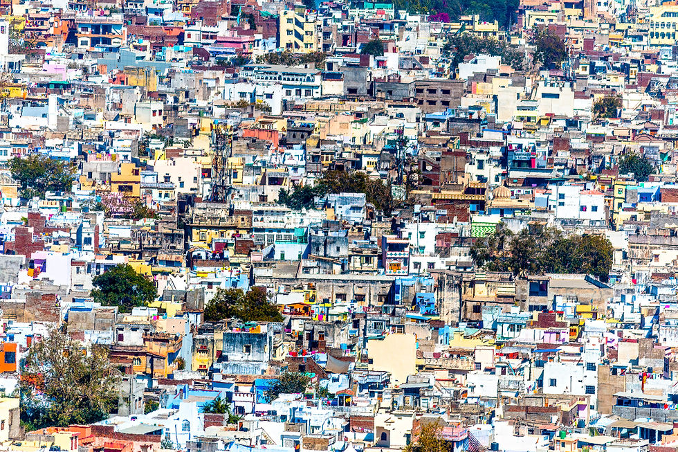 Dense cityscape with tightly packed colorful buildings under a clear sky, showing a vibrant mix of patterns and textures. No visible text.