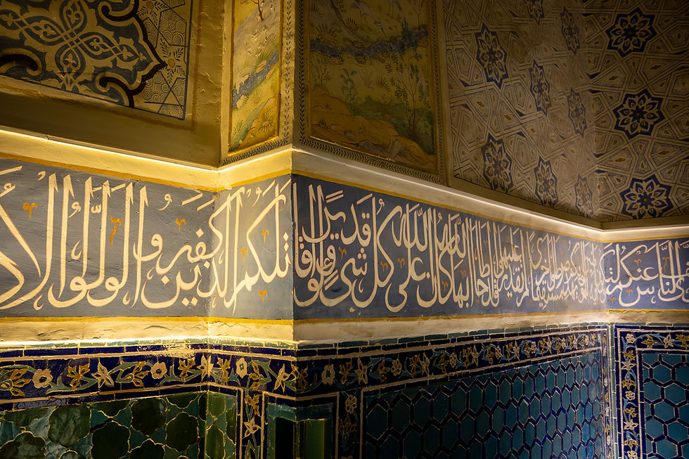 Intricate Arabic calligraphy adorns a tiled wall corner. Patterns in blue and gold create an ornate, historical ambiance.