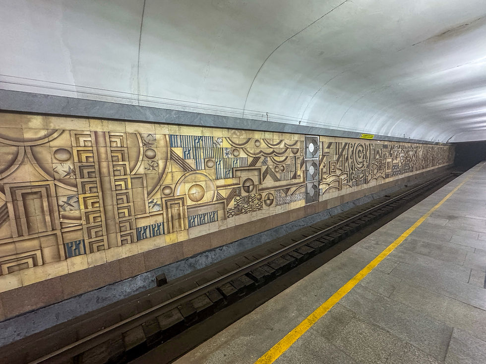 Subway platform with abstract geometric mural on the wall. Yellow line on the floor, creating a calm, artistic atmosphere.