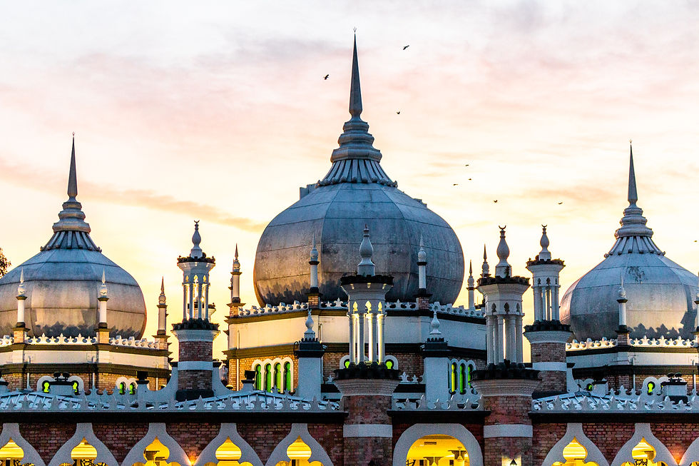 Ornate mosque with large domes and minarets at sunset, birds flying above. Warm glow from windows, against a colorful sky. Calm mood.