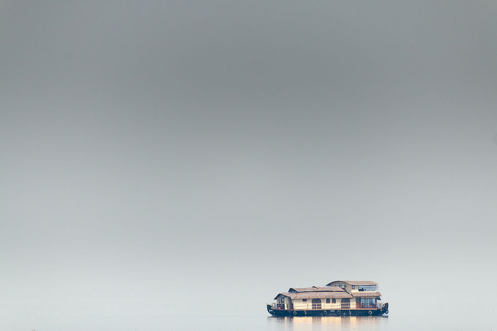 A solitary houseboat floats on calm water against a vast gray backdrop, creating a serene and tranquil scene.