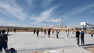 Imagen de niños jugando futbol en una cancha de cemento al aire libre.