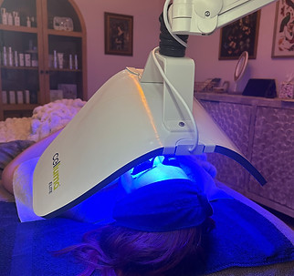Woman laying on treatment bed inside Sage & Honey Skin and Wellness receiving an acne treatment with Celluma LED Therapy