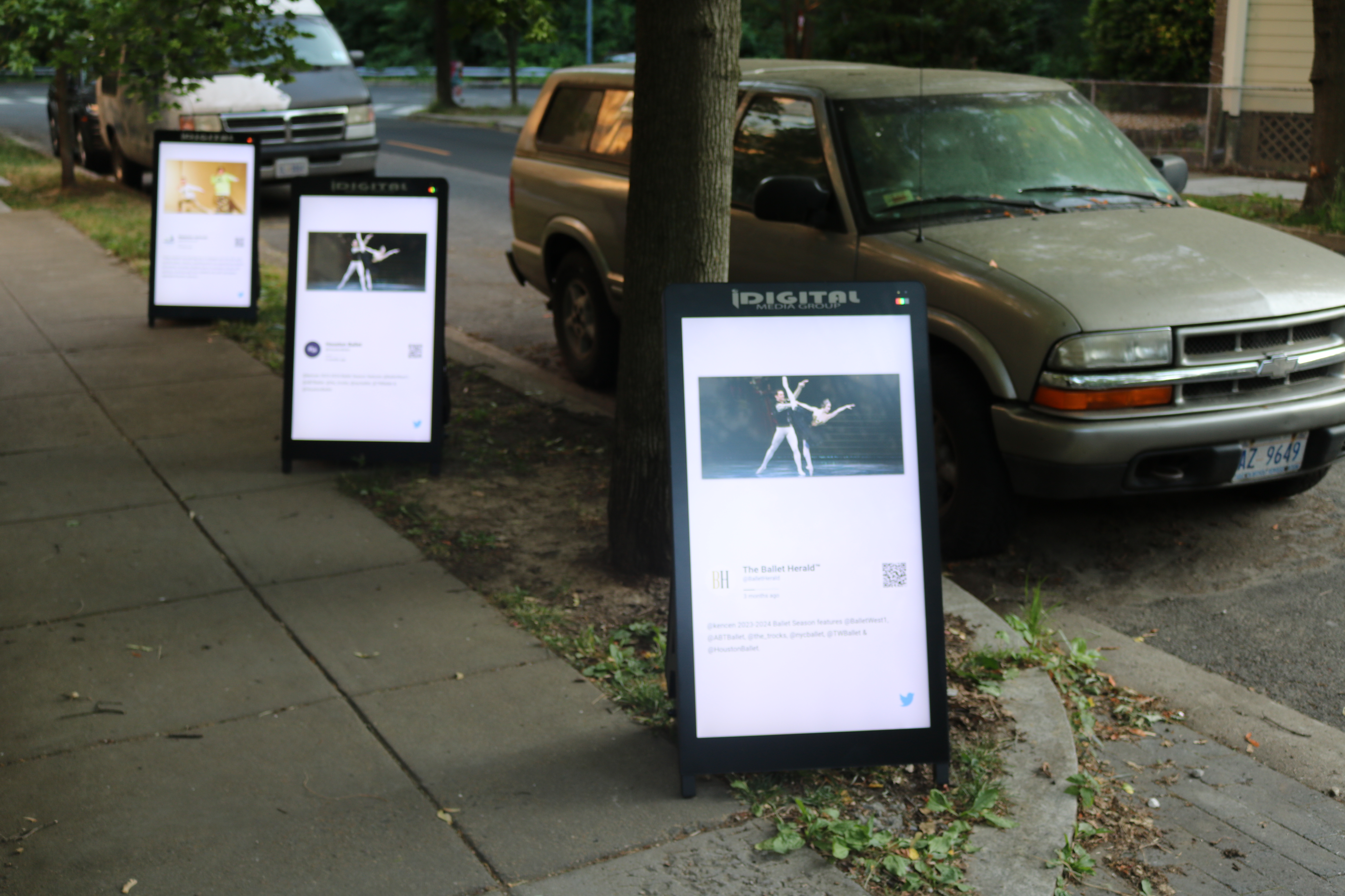 Three i-Frame digital posters on a city sidewalk