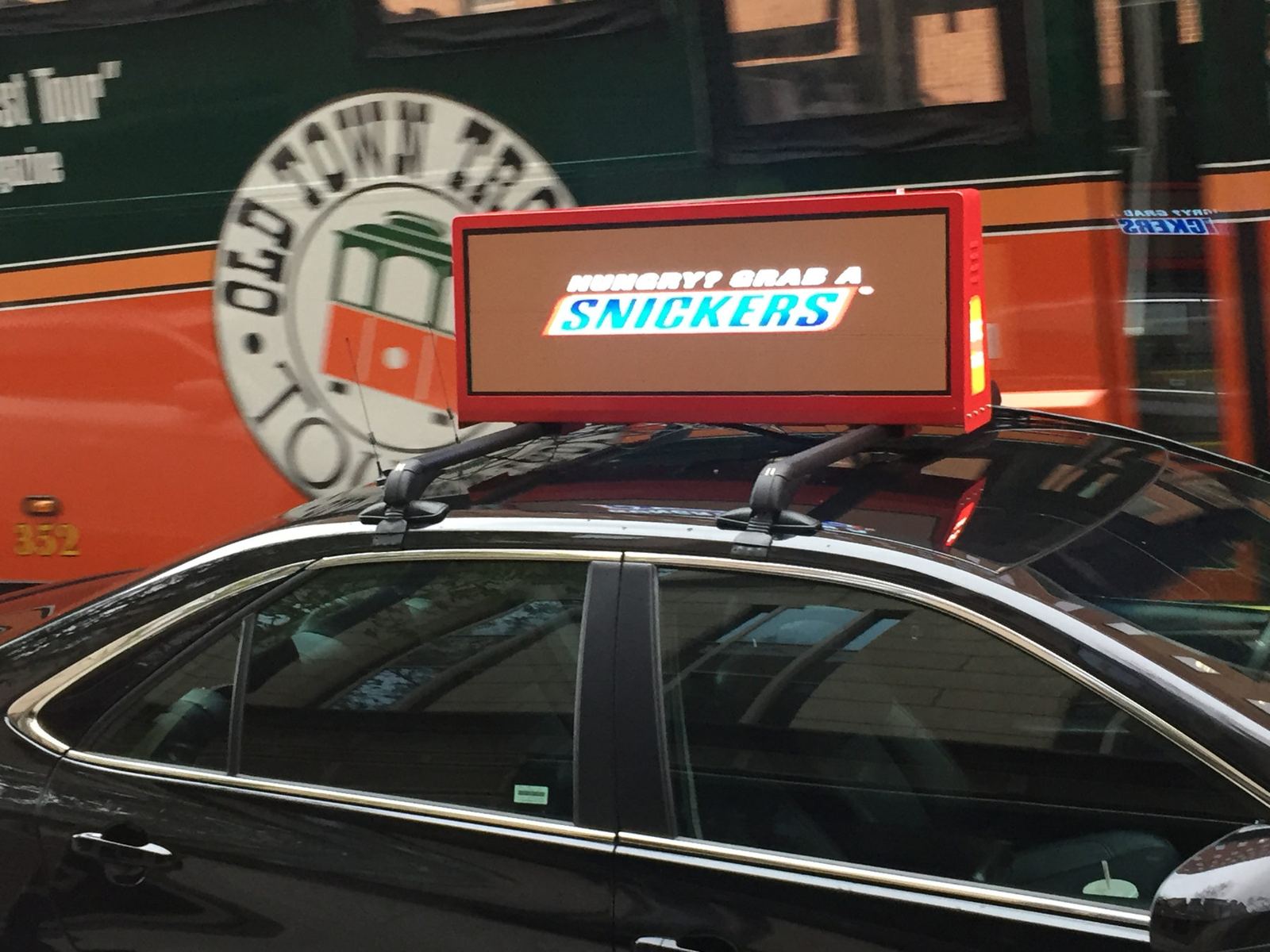 Black car with a rooftop display running a snack brand ad