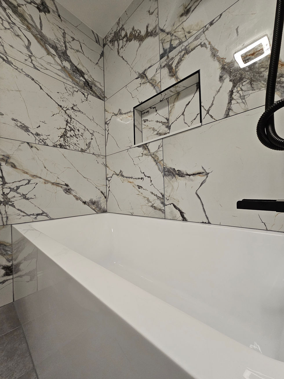 a bathtub in a bathroom with marble tiles on the wall