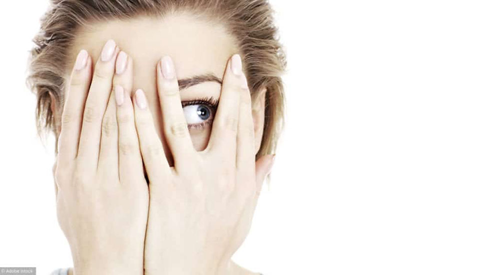 une femme se cache derrière ses mains par peur