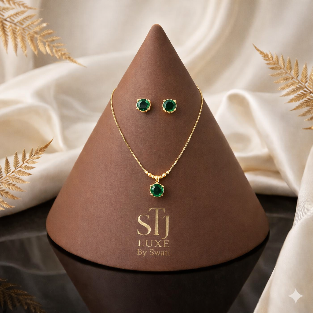 Gold necklace, matching stud earrings with green gemstones