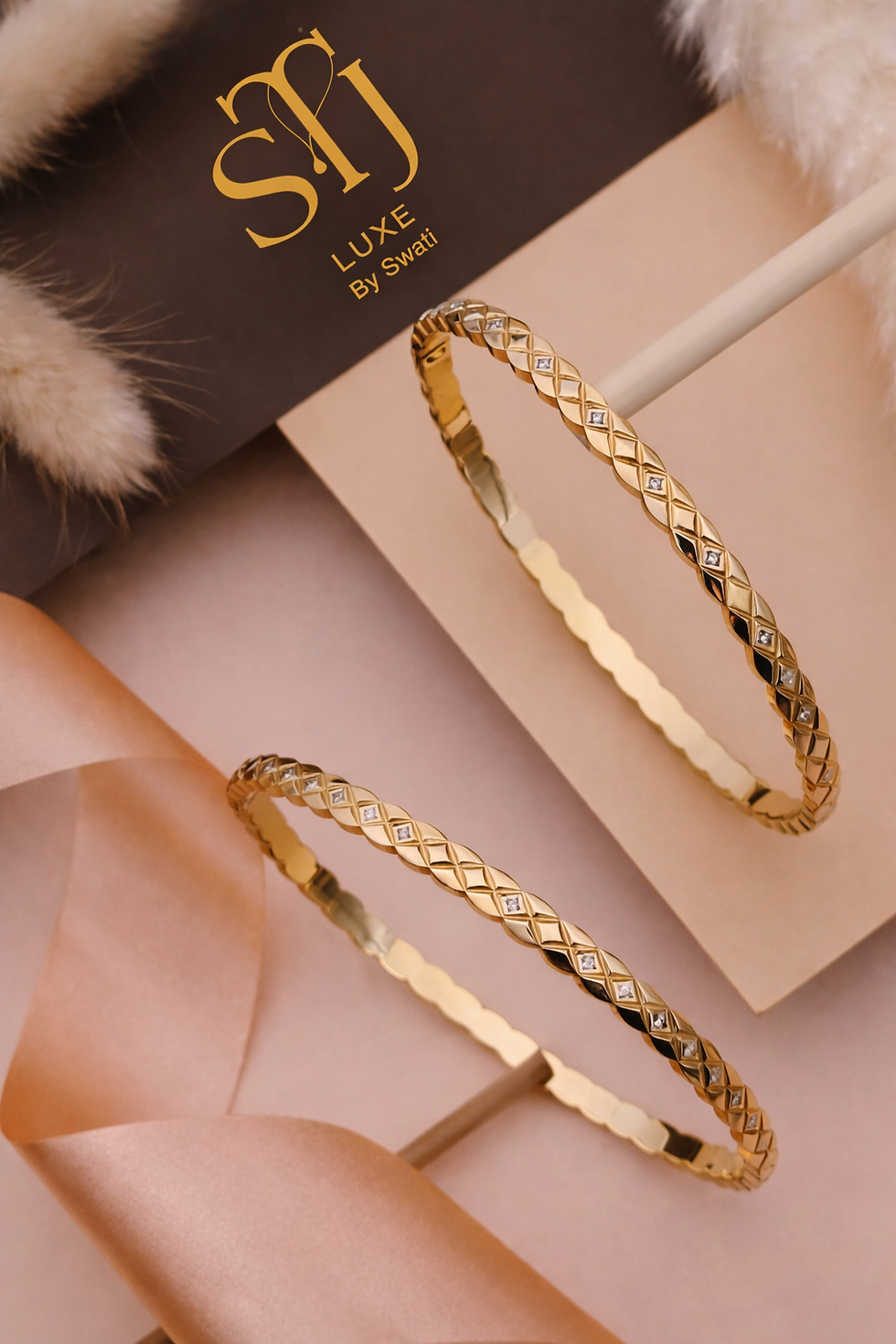 Two gold bangles on pink surface with SLJ Luxe by Swati box
