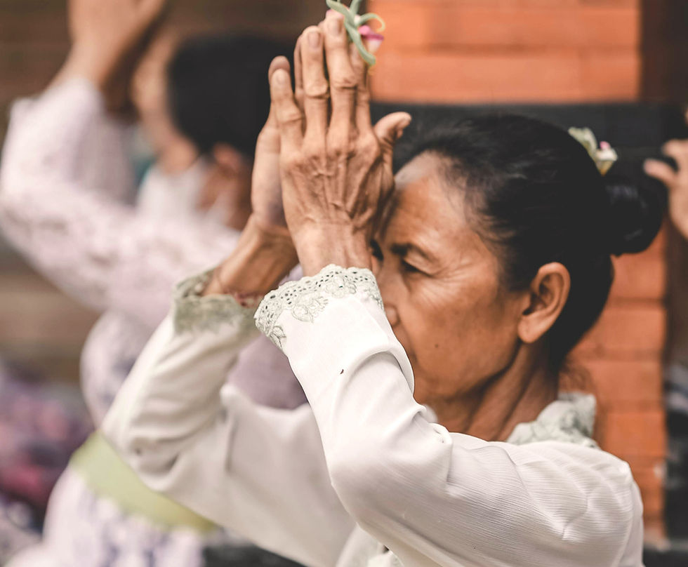 une indienne pratique le yoga les mains jointes l'une contre l'autre face au visage en Anjali mudra. Elle a le regard concentré dans sa pratique du yoga dans un univers calme et couleur chaleureuses.